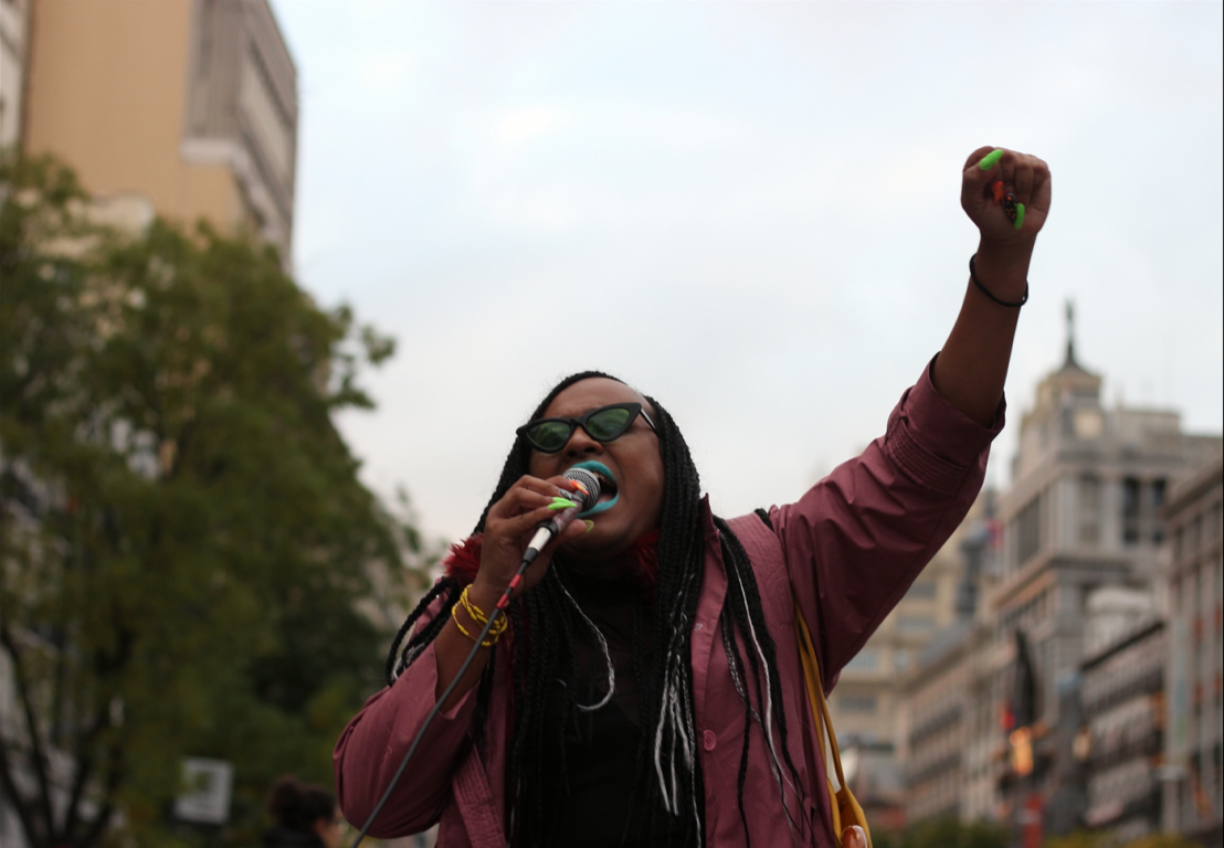 Mujer con el puño en alto en una manifestación antirracismo por el 12N